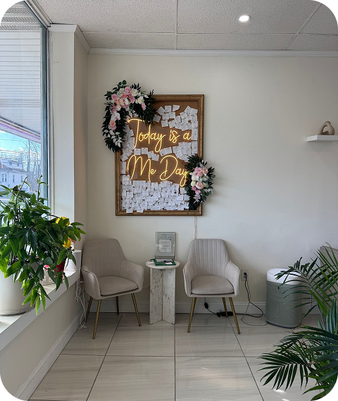 Reception area at J’Adore Nails with chairs, plants, and decorative board displaying notes and flowers.